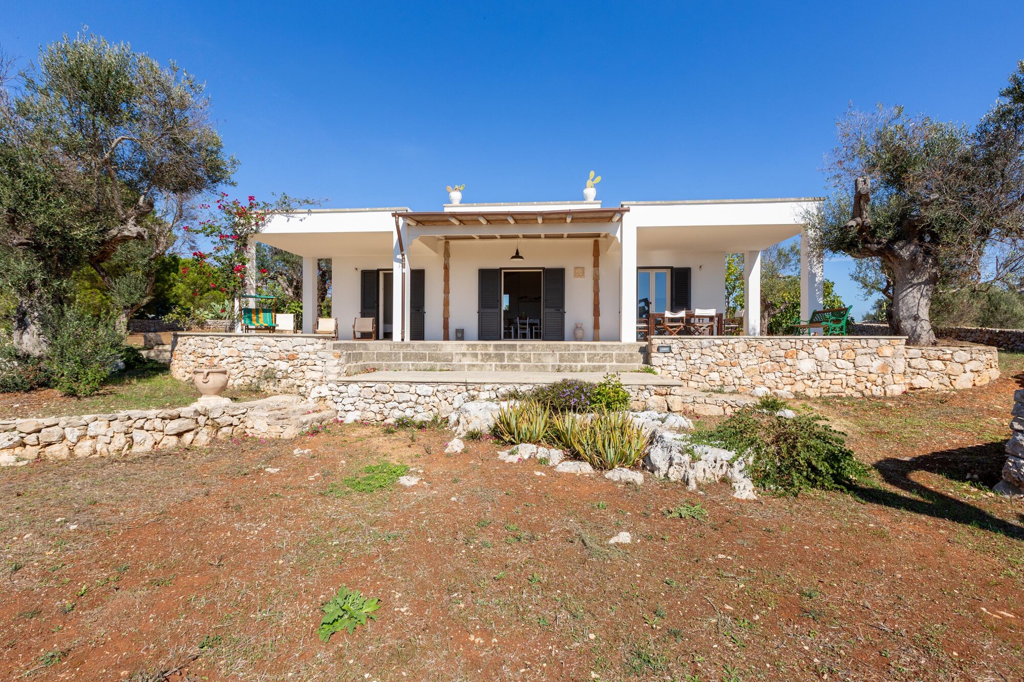Facciata della villa e veranda coperta viste dal giardino